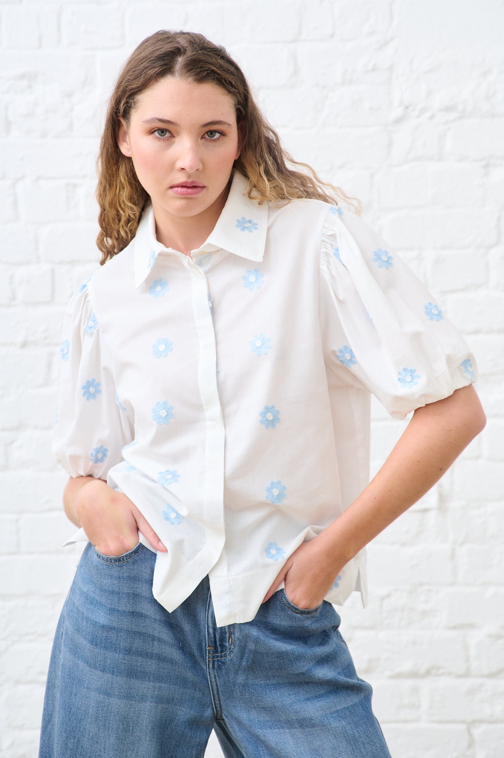 Model is wearing a white short sleeve top with blue flowers