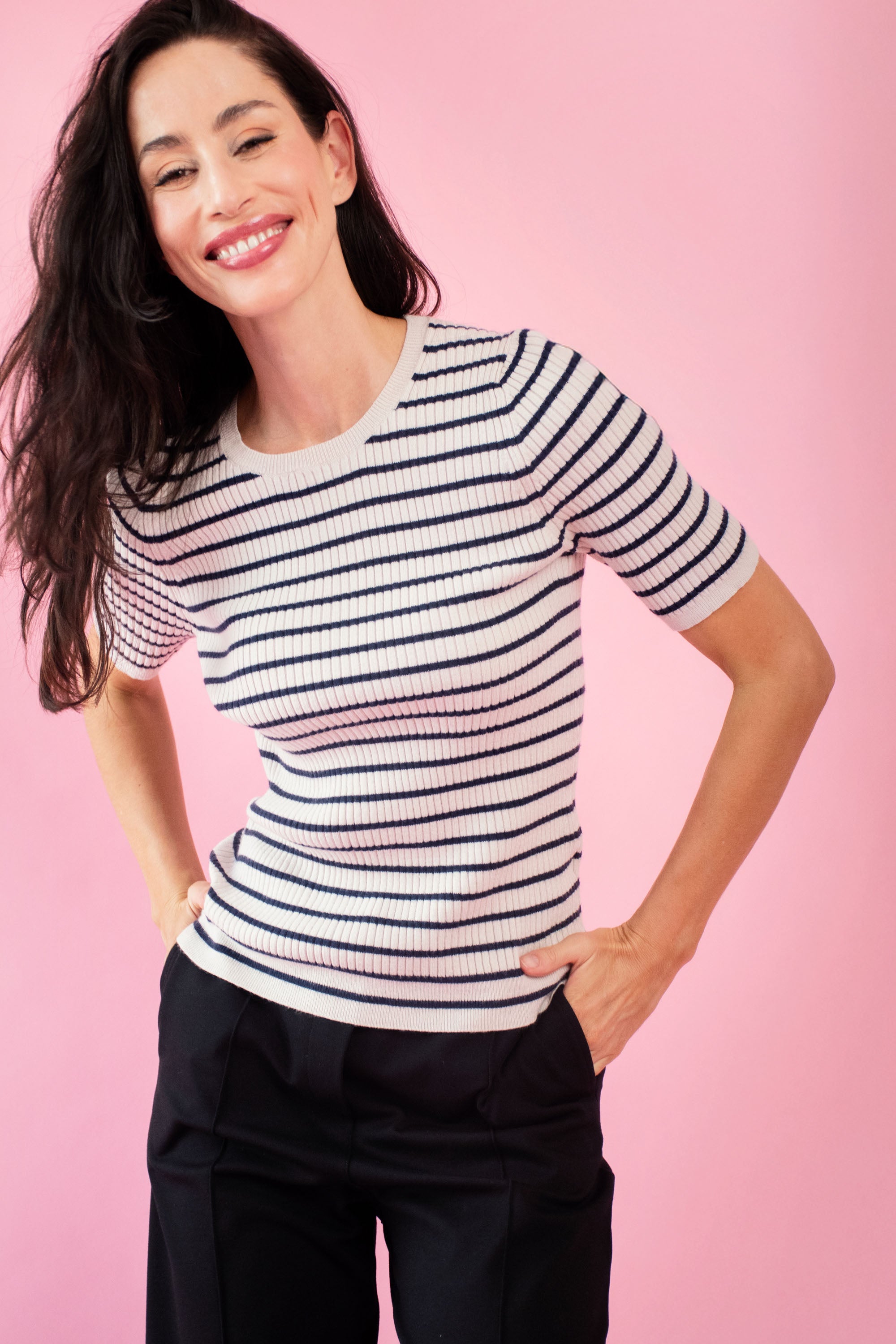 Model is wearing a striped black and cream ballerina knit top with black pants