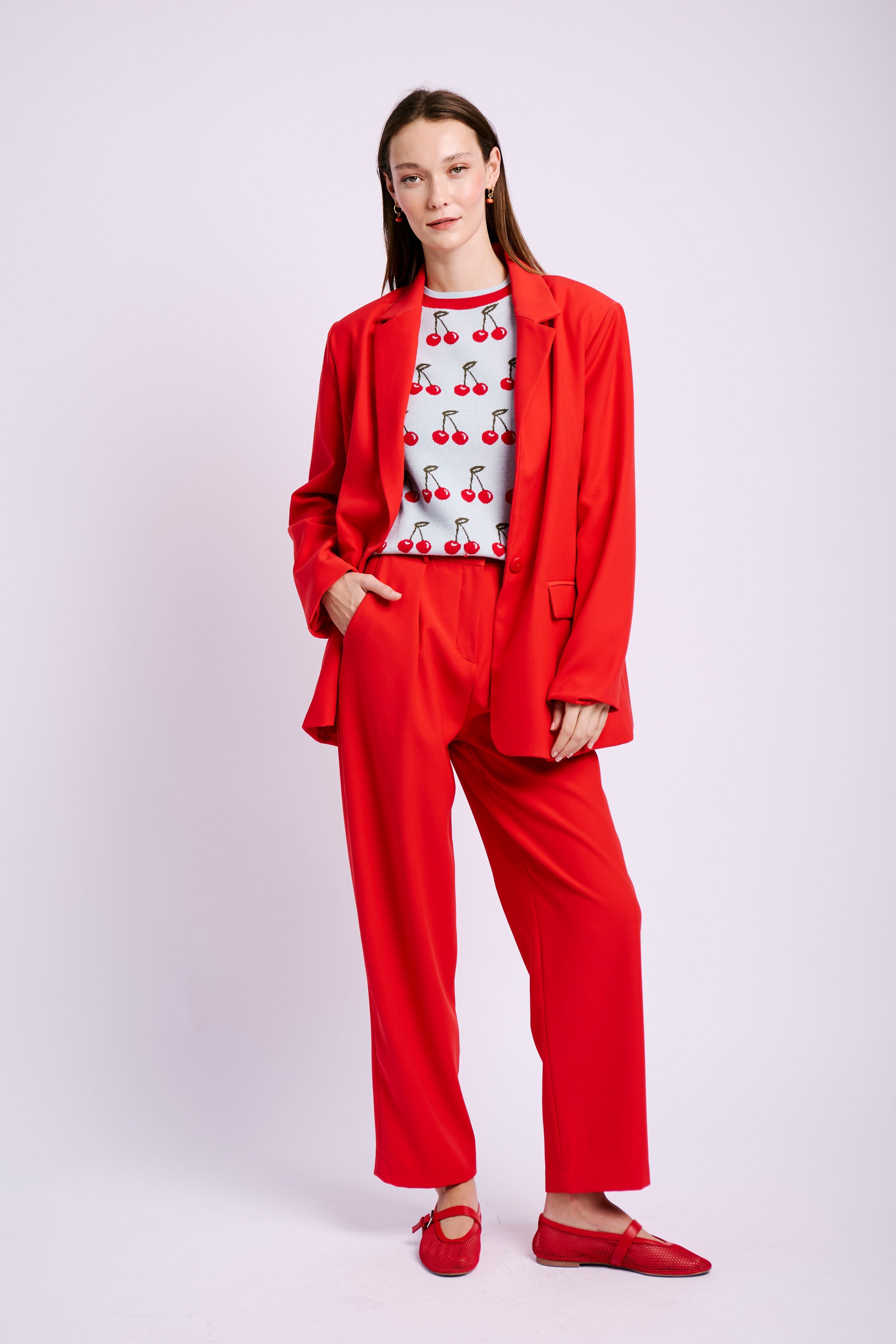 Model wearing red suit and cherry jumper