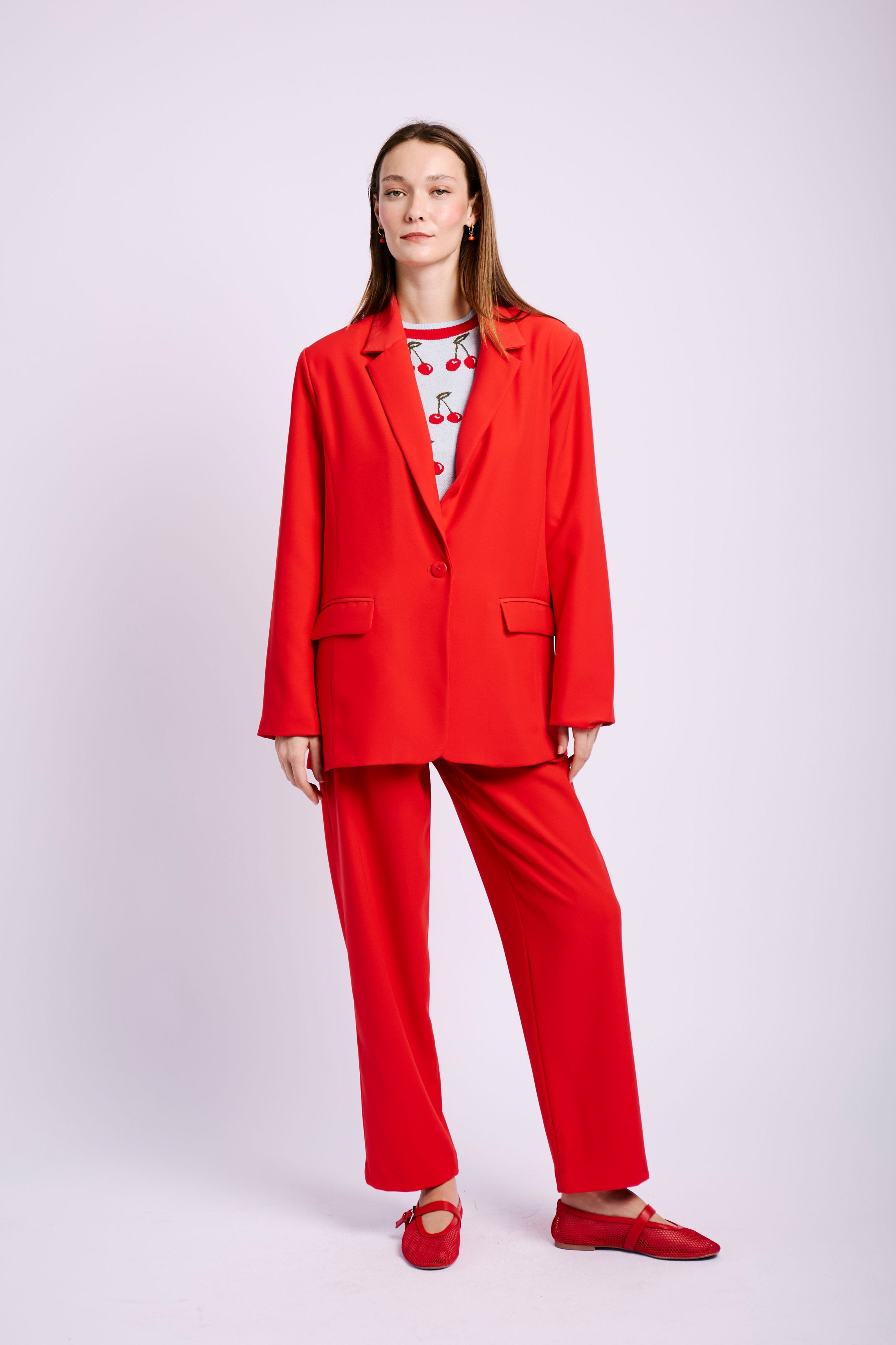 Model wearing red suit and cherry jumper