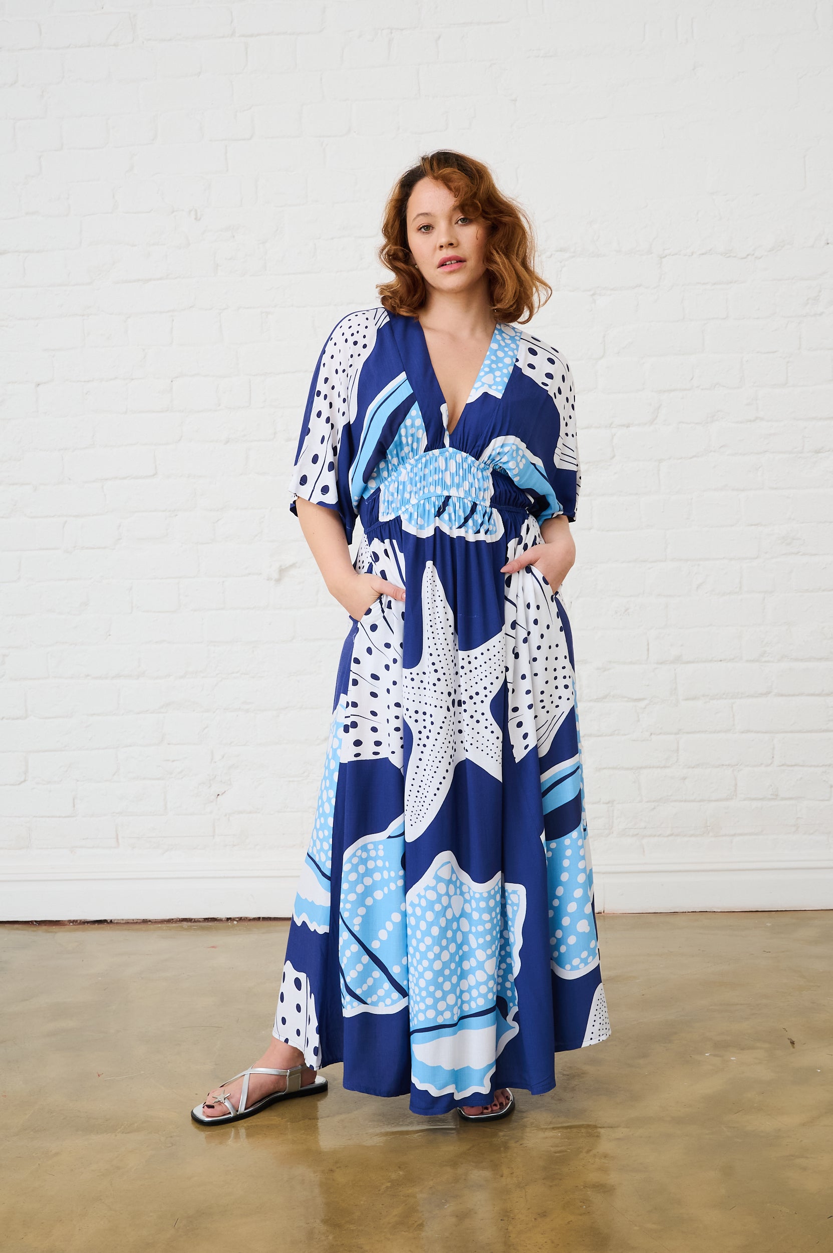 Model is wearing a blue shell dress with silver sandals
