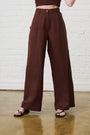 Model is wearing brown wide leg linen pants with brown sandals by Me&B