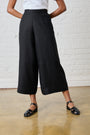 Model is wearing black wide leg linen pants with a white top and black sandals
