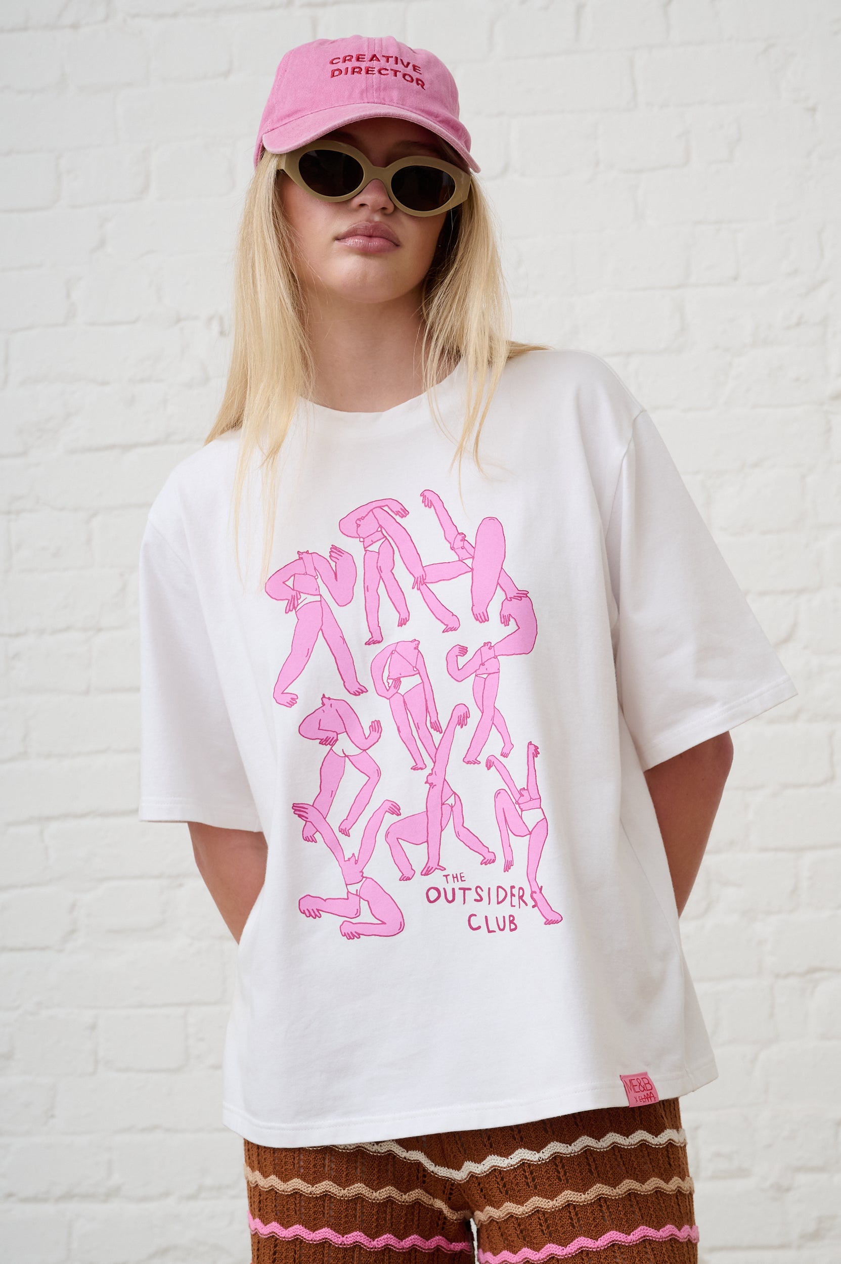 Model is wearing a white T-Shirt with Pink Print and a pink cap