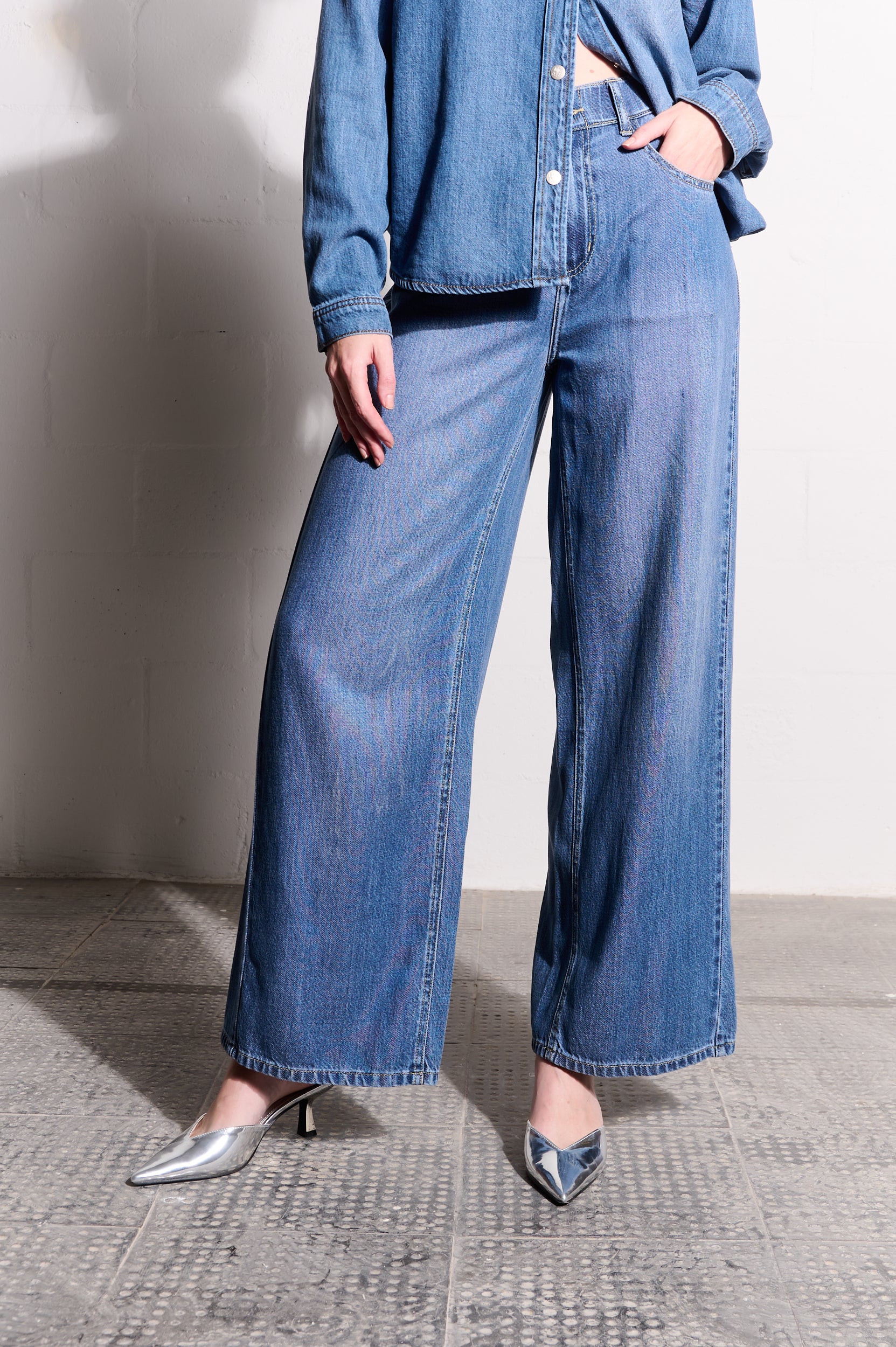 Model is wearing wide leg denim jeans and silver heels
