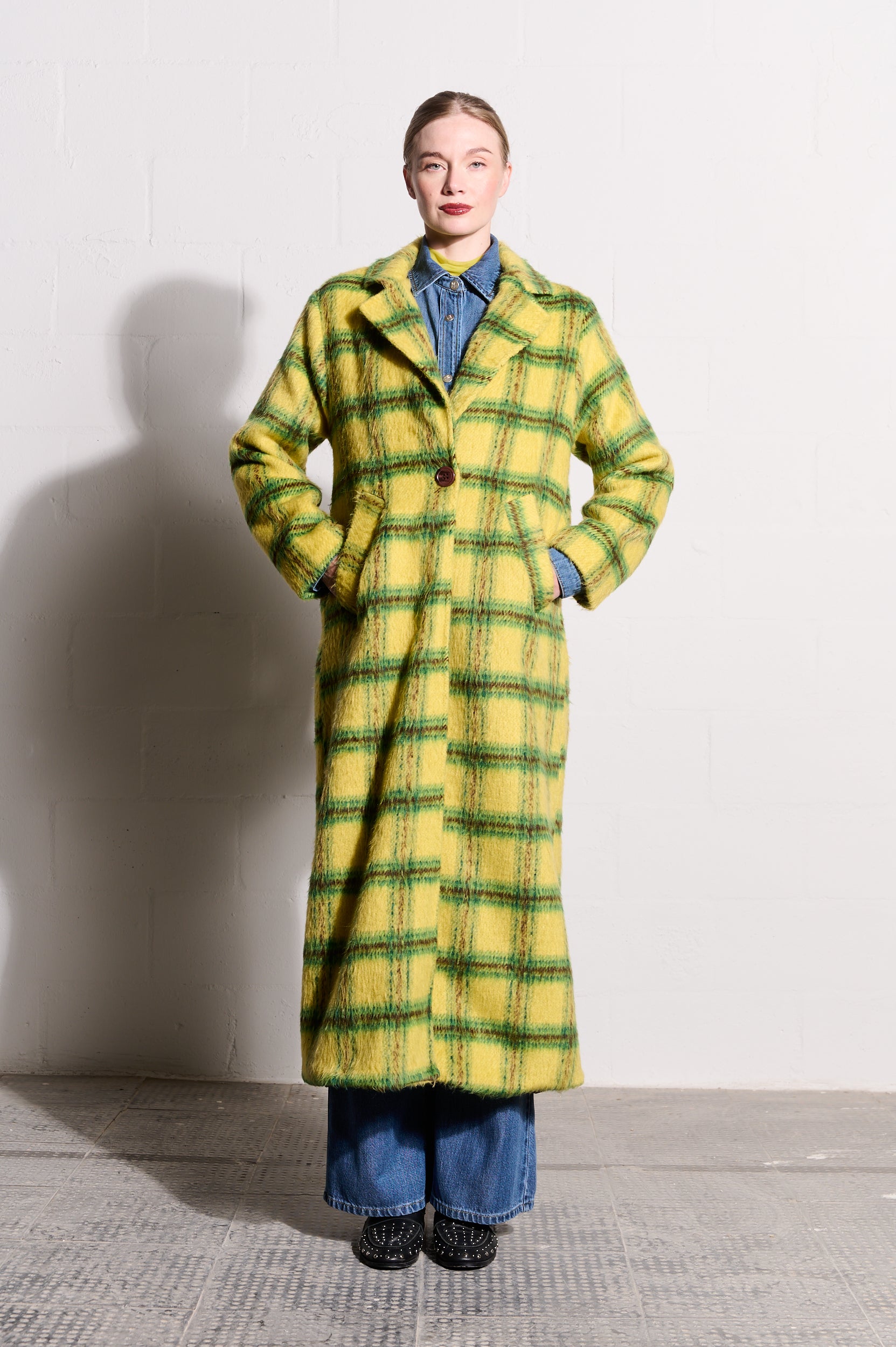 Model is wearing a bright yellow check jacket and black shoes