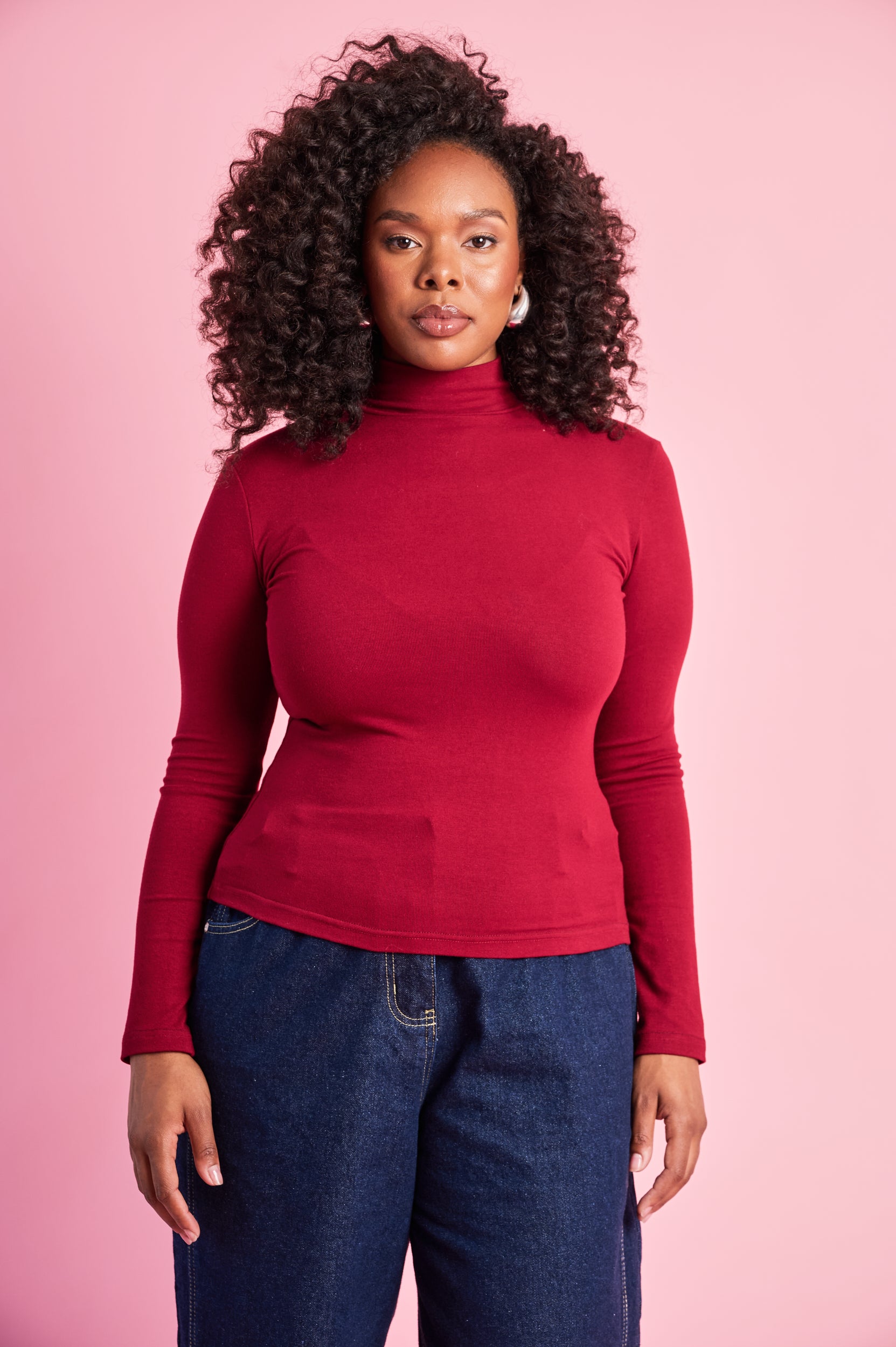 Model is wearing a long sleeve burgundy polo top with dark blue jeans