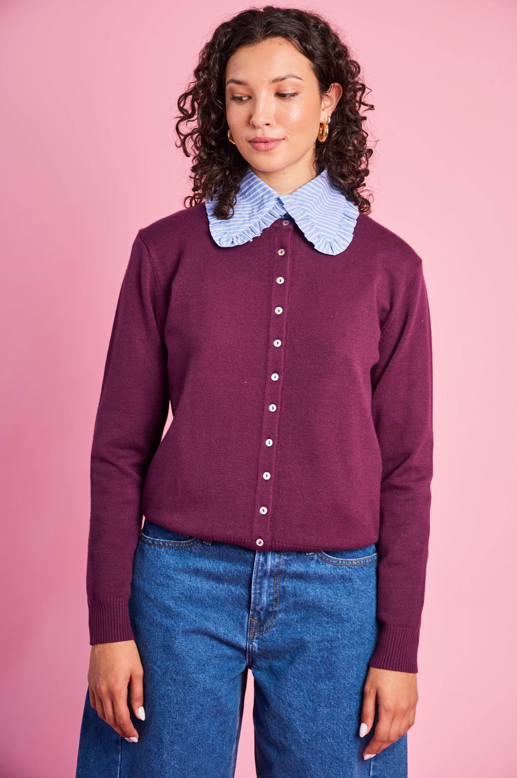 Model is wearing a plum knit cardigan with blue denim jeans