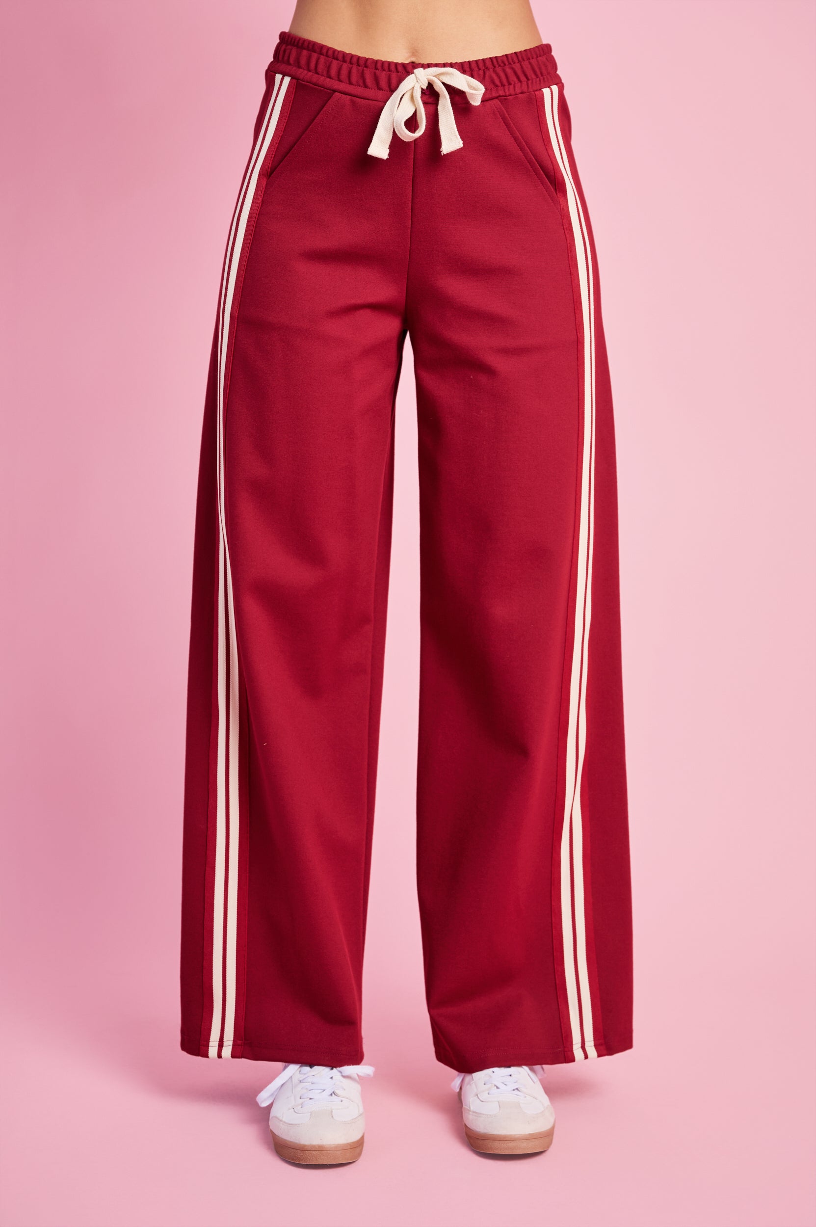 Model is wearing burgundy pants and white sneakers