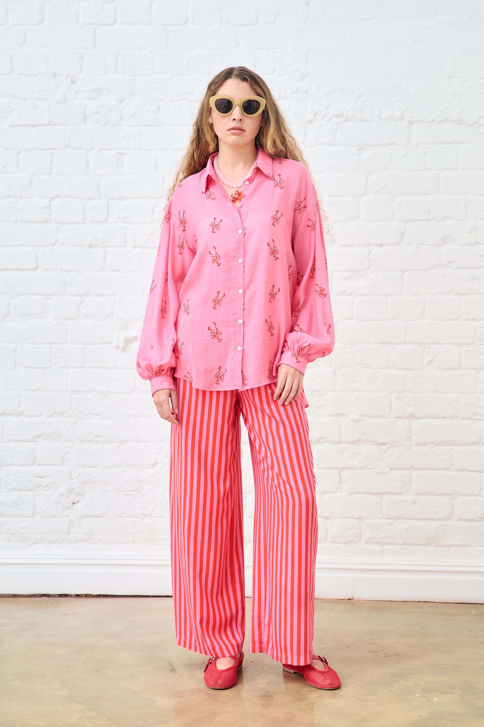 Model is wearing pink and red stripe pants with a pin top and red shoes