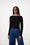 Model is wearing a black long sleeve boat neck top with dark wash barrel jeans