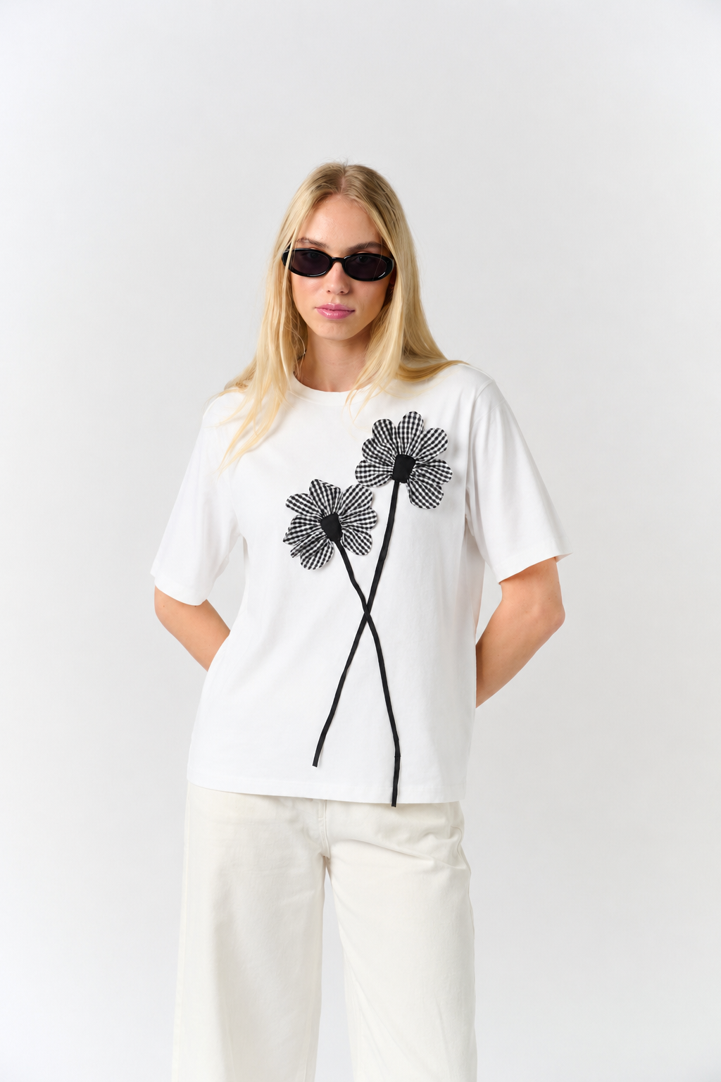 Model is wearing a white t shirt with a floral appliqué detail in gingham print