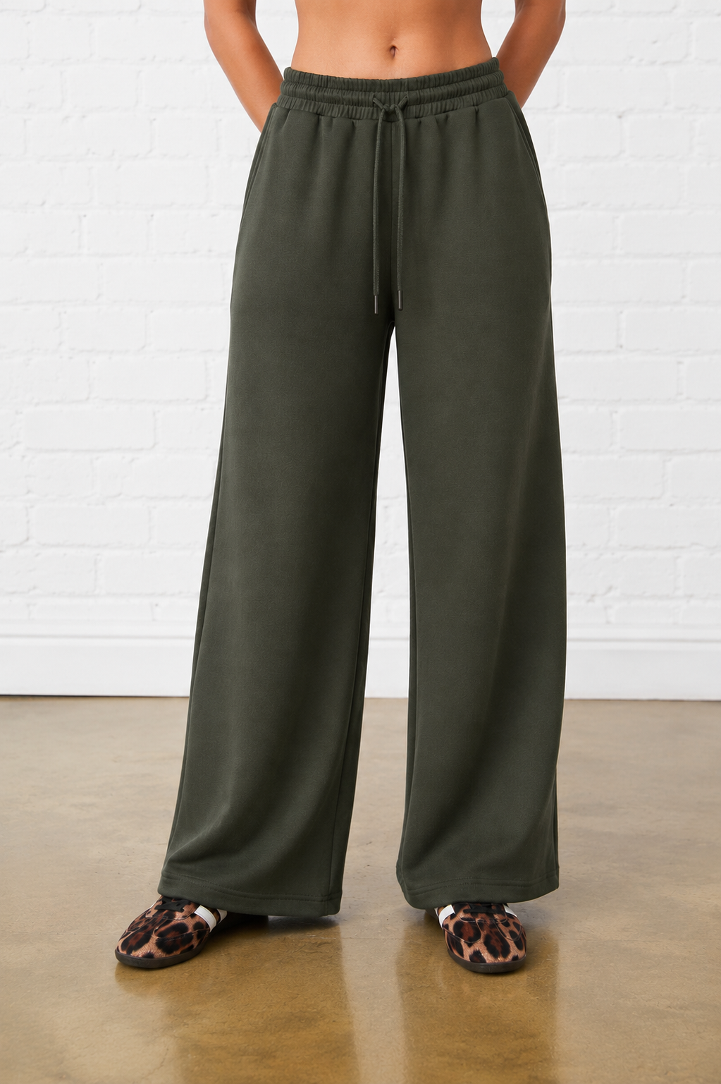 Model is wearing olive green elasticated waist wide leg joggers with leopard print shoes 
