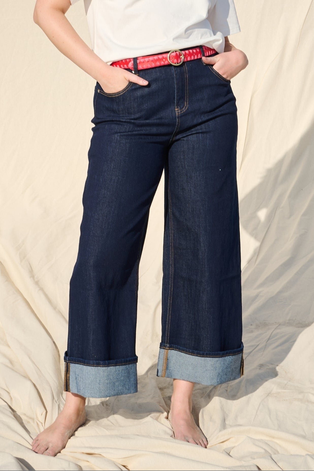 Model is wearing a wide leg dark wash turn up stretch jean with a oink belt and white t shirt