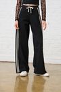 Model is wearing black wide leg pants with a lace trim along the side and white sneakers