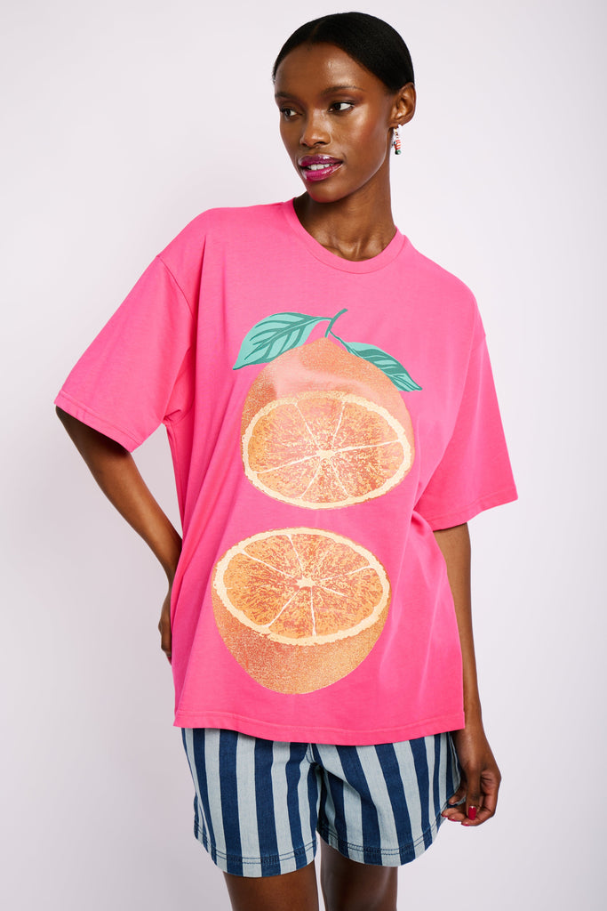 Model is wearing an oversized pink T-shirt with an orange grapefruit print on the front.