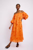 Model is wearing an off the shoulder midi length dress made of anglaise embroidered fabric. It has three quarter length sleeves and is lined.