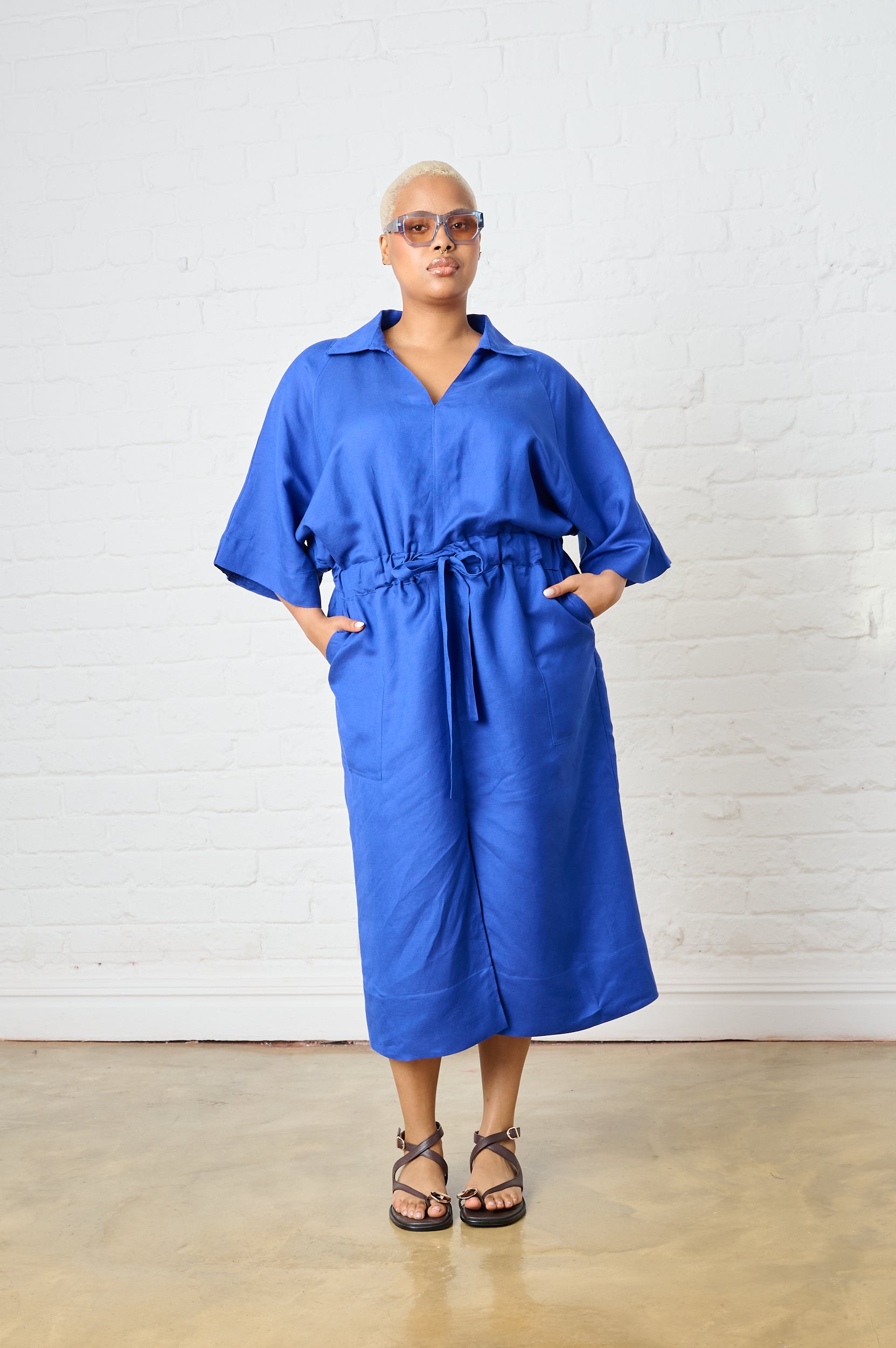 Model is wearing a cobalt linen dress with brown sandals