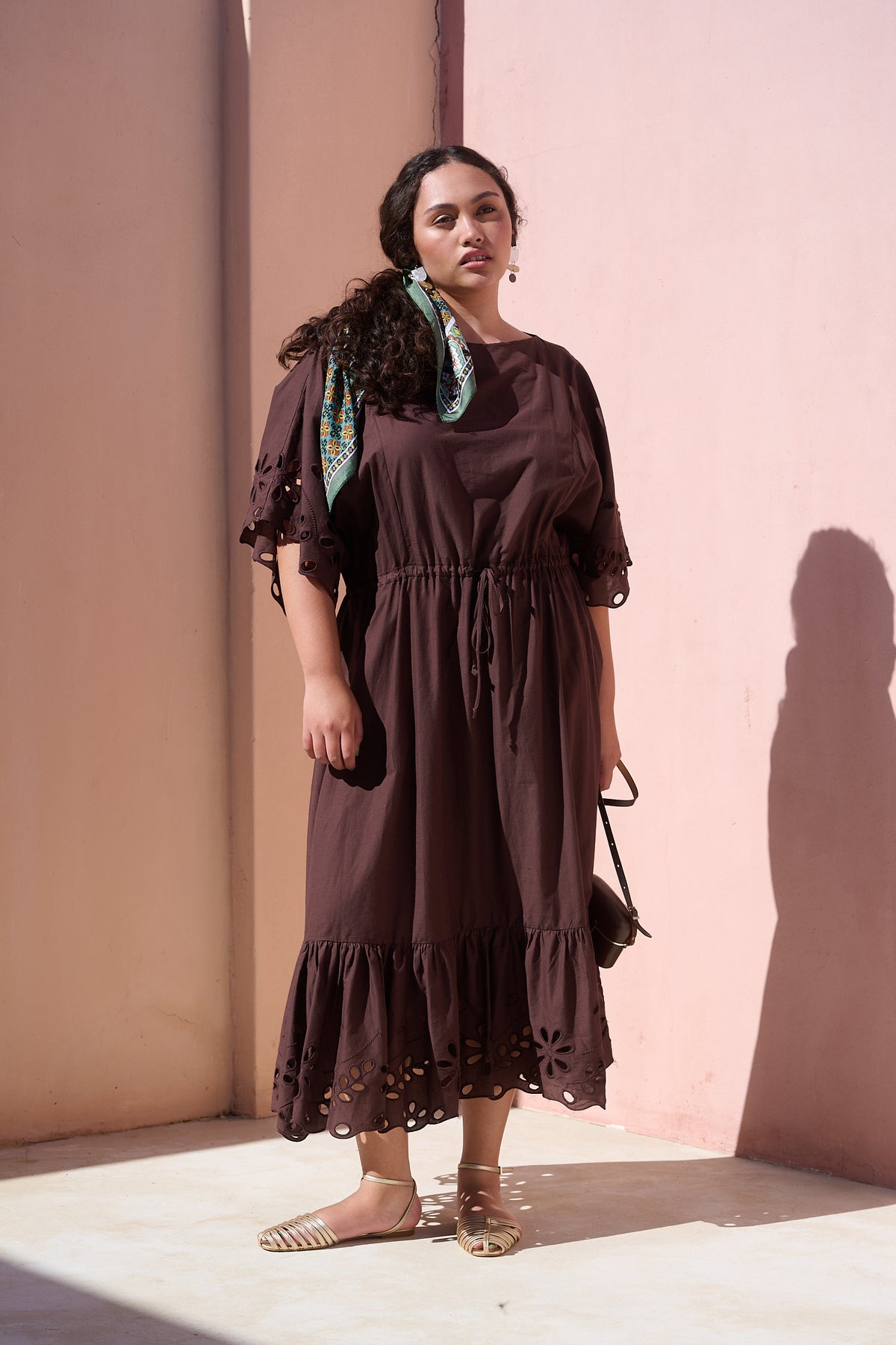 Model wearing chocolate cotton tiered dress with broderie anglaise
