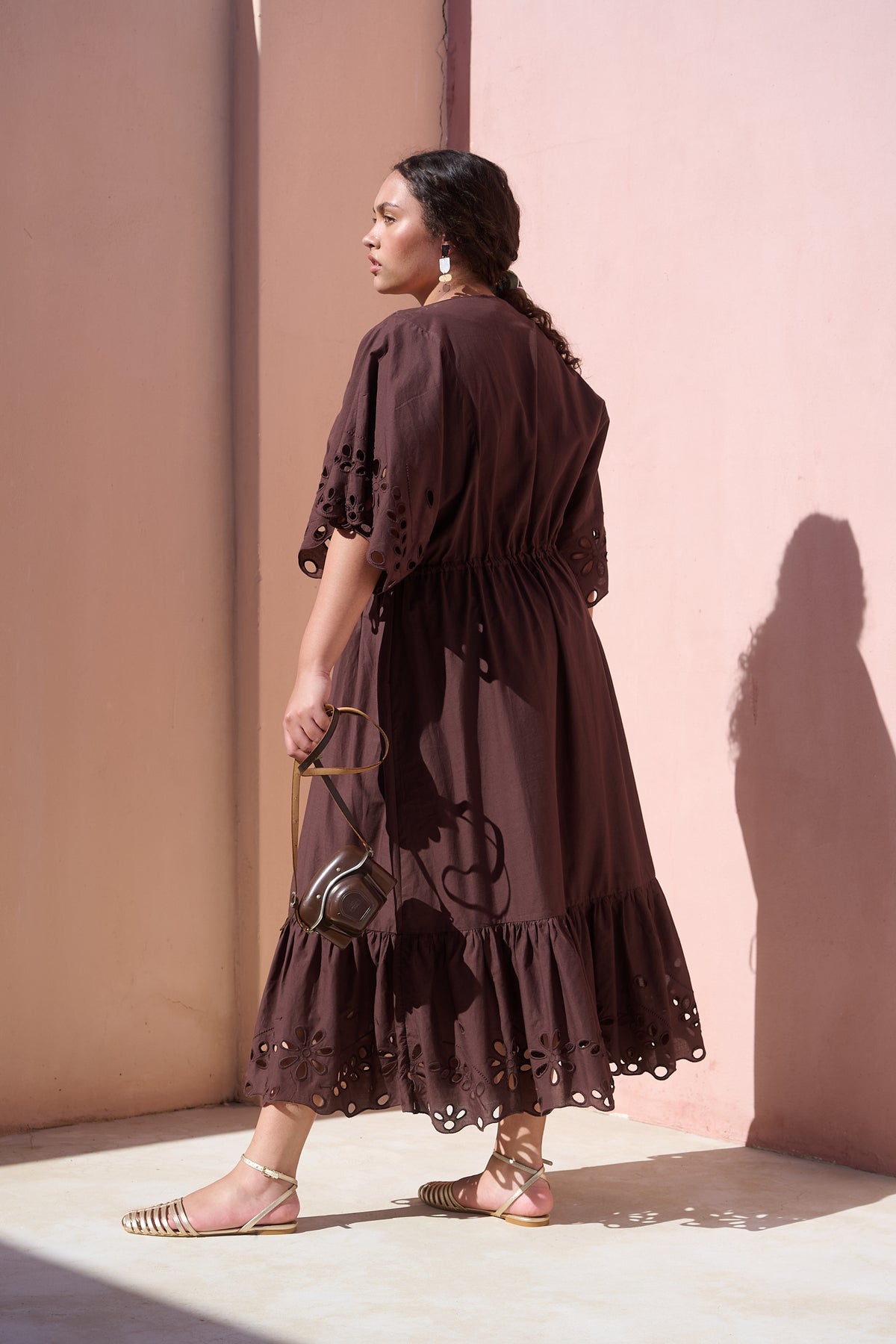 Model wearing chocolate cotton tiered dress with broderie anglaise
