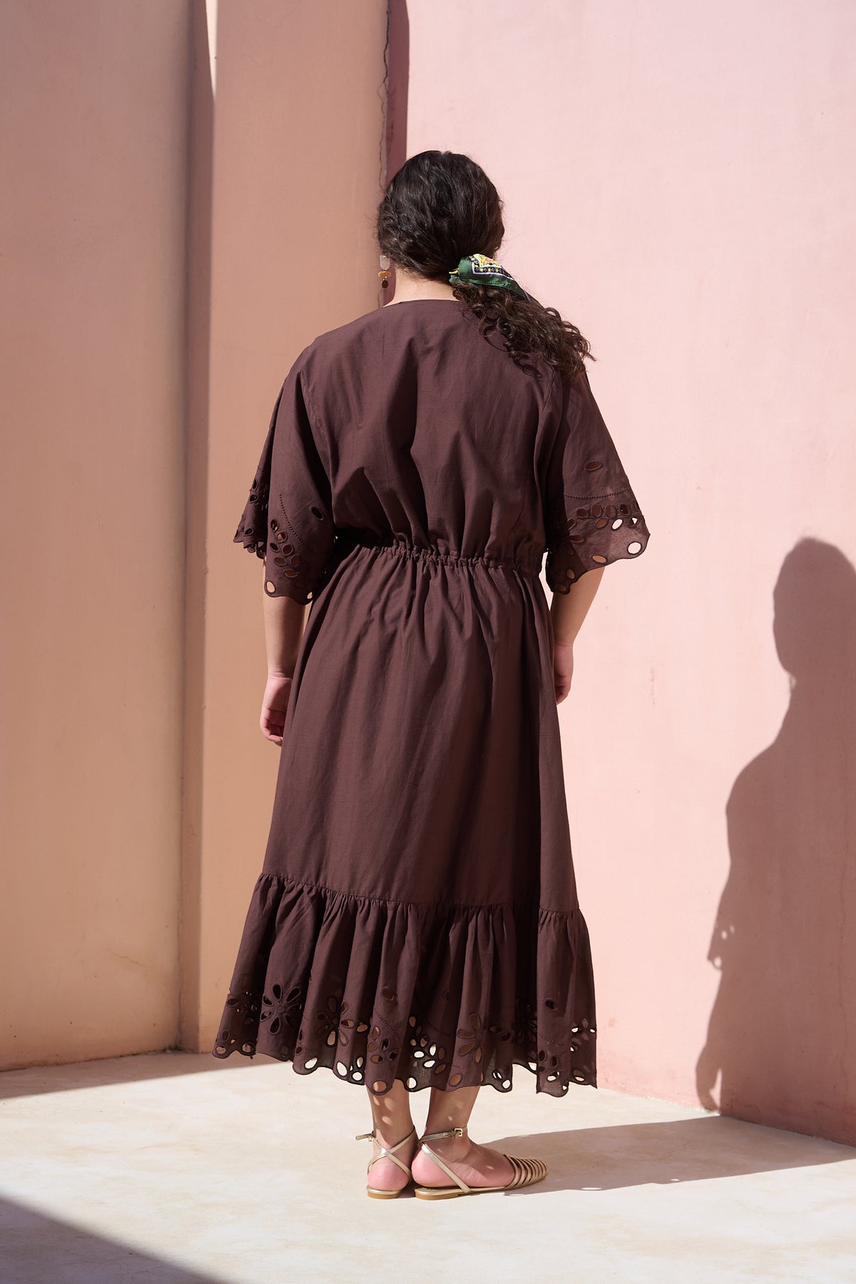 Model wearing chocolate cotton tiered dress with broderie anglaise
