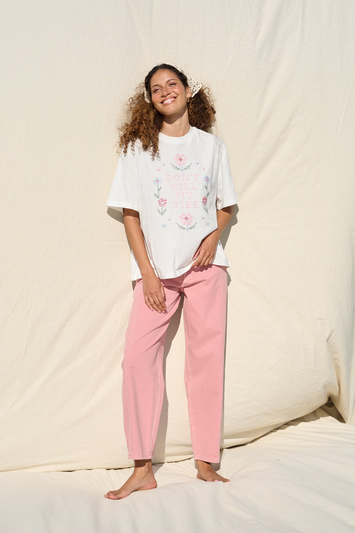 Model wearing white T-shirt with floral cross stitch detail