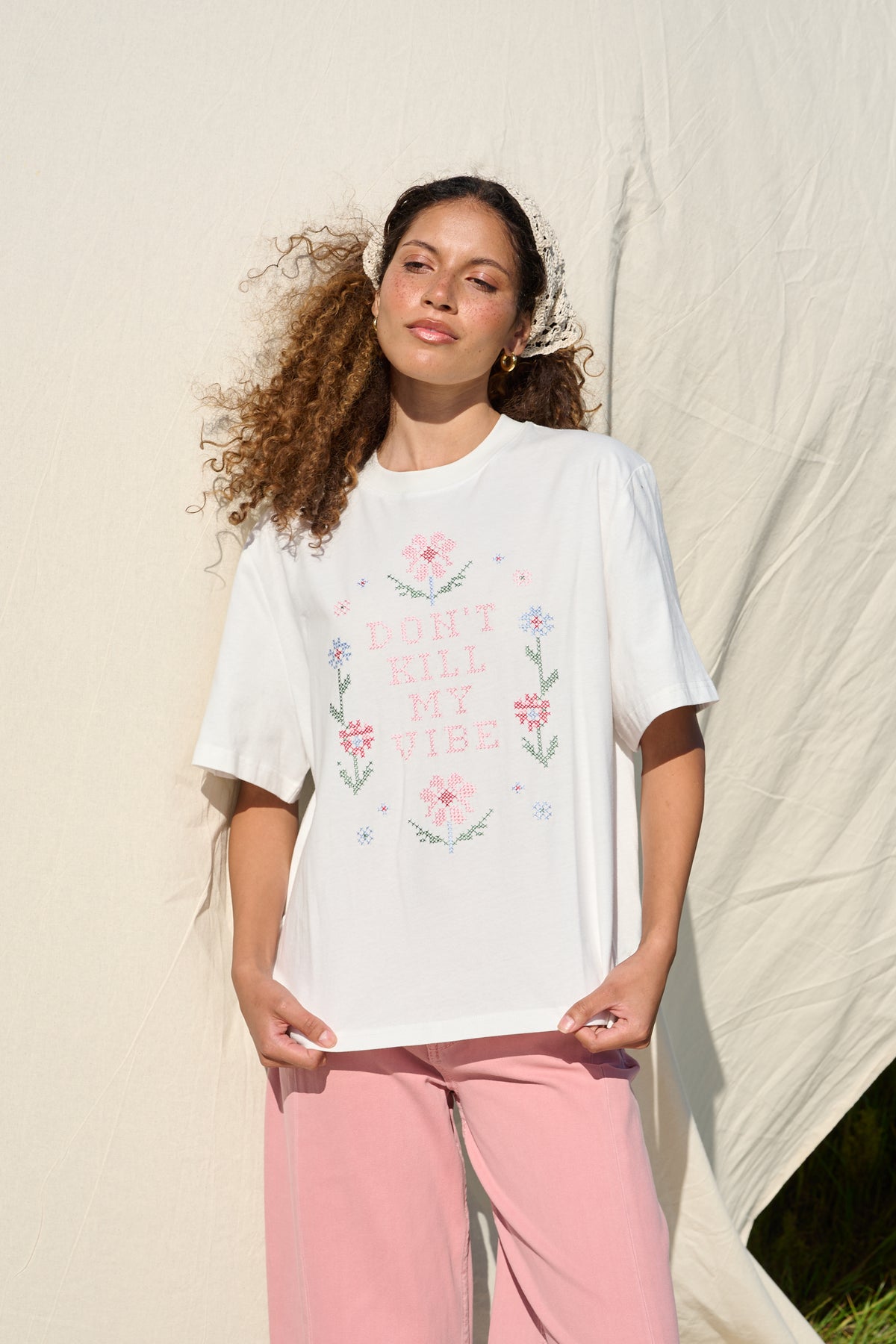 Model wearing white T-shirt with floral cross stitch detail