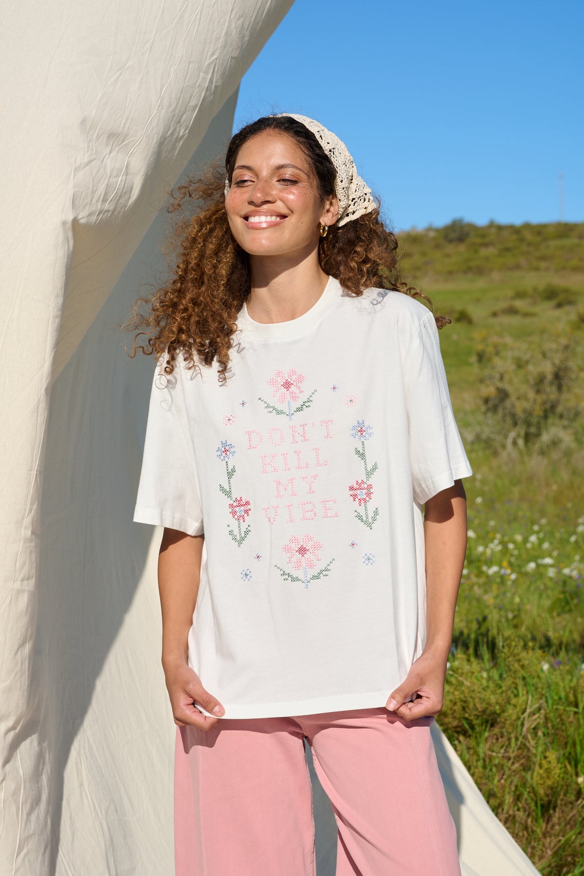 Model wearing white T-shirt with floral cross stitch detail