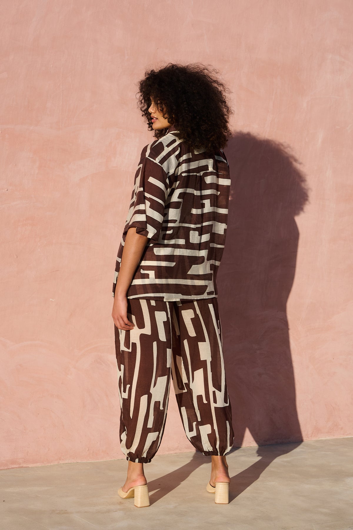 Model wearing oversized chocolate banana-print viscose short-sleeve shirt from the back view