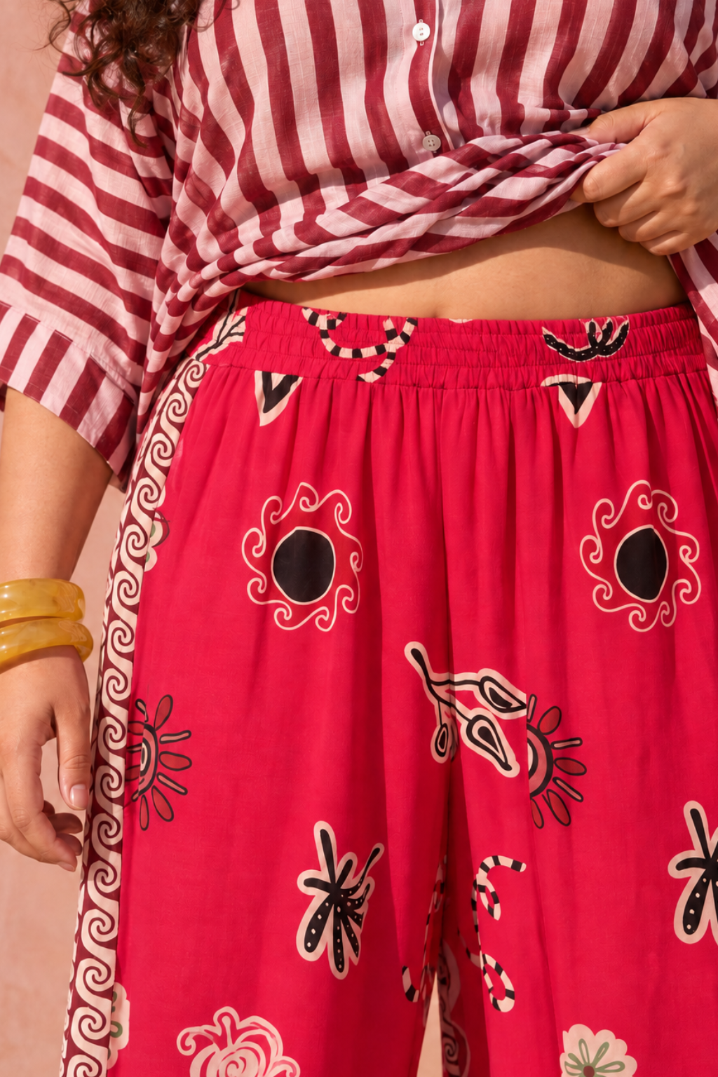 Model wearing pink wide-leg pants with motif print and burgundy borders