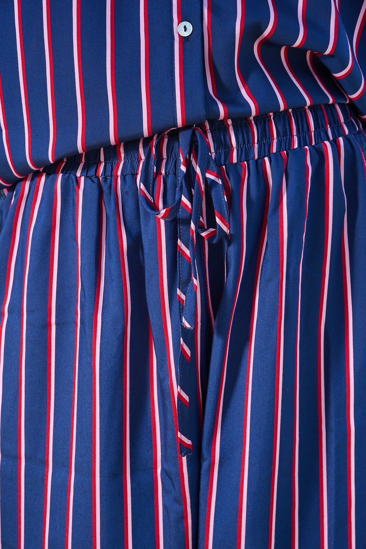 Close-up of a navy blue garment with vertical red and white stripes, featuring an elastic drawstring waist.