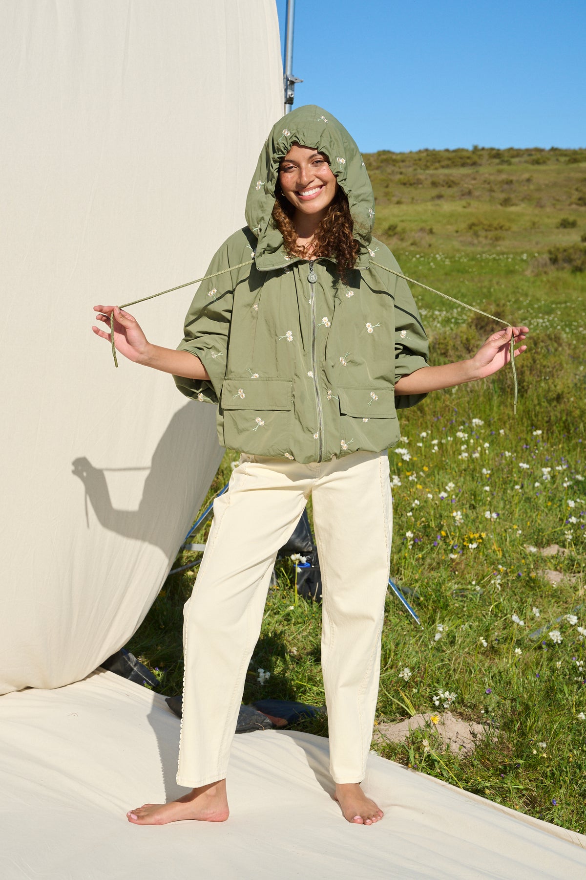 Model wearing fatigue green hooded jacket with daisy embroidery