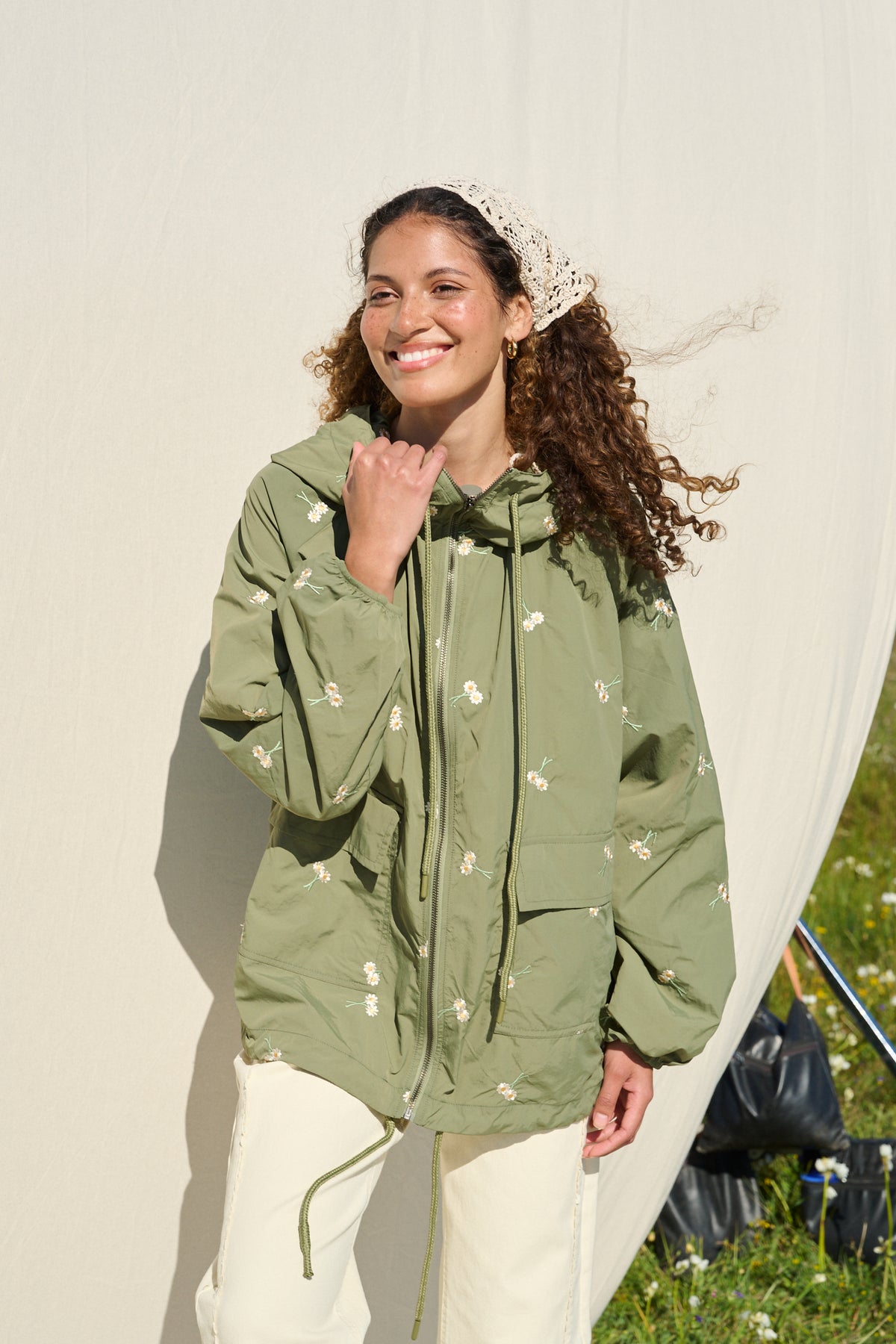 Model wearing fatigue green hooded jacket with daisy embroidery