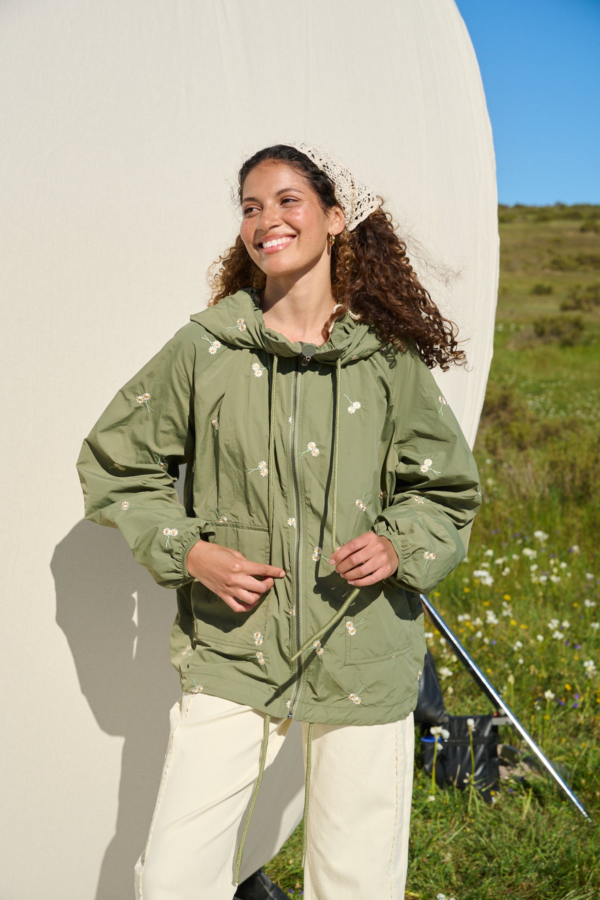 Model wearing fatigue green hooded jacket with daisy embroidery