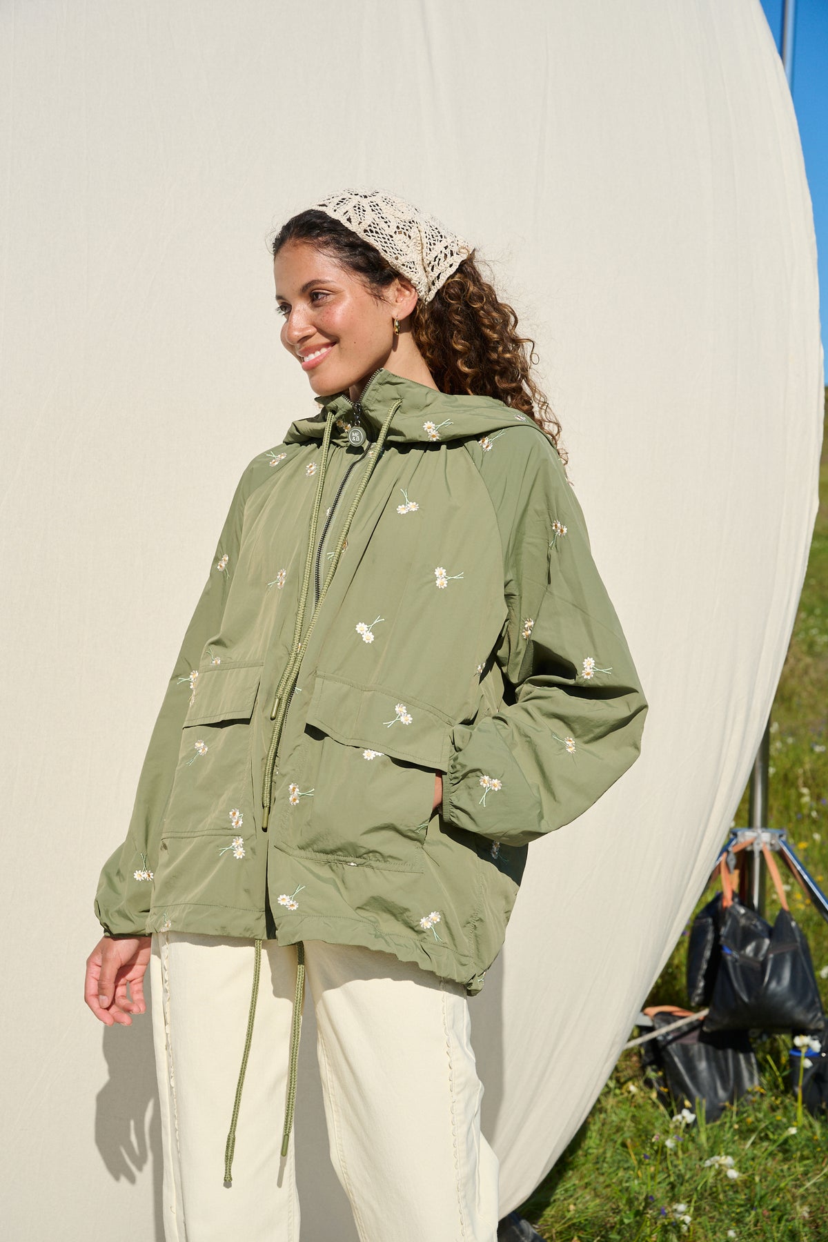 Model wearing fatigue green hooded jacket with daisy embroidery