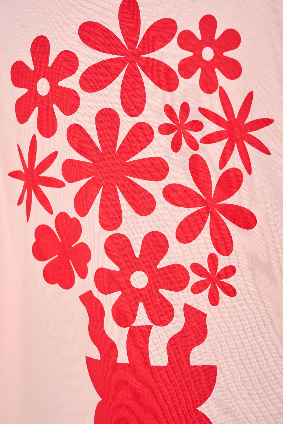 A close-up of a light pink fabric surface printed with a bold red graphic of stylized flowers and a flower pot silhouette.