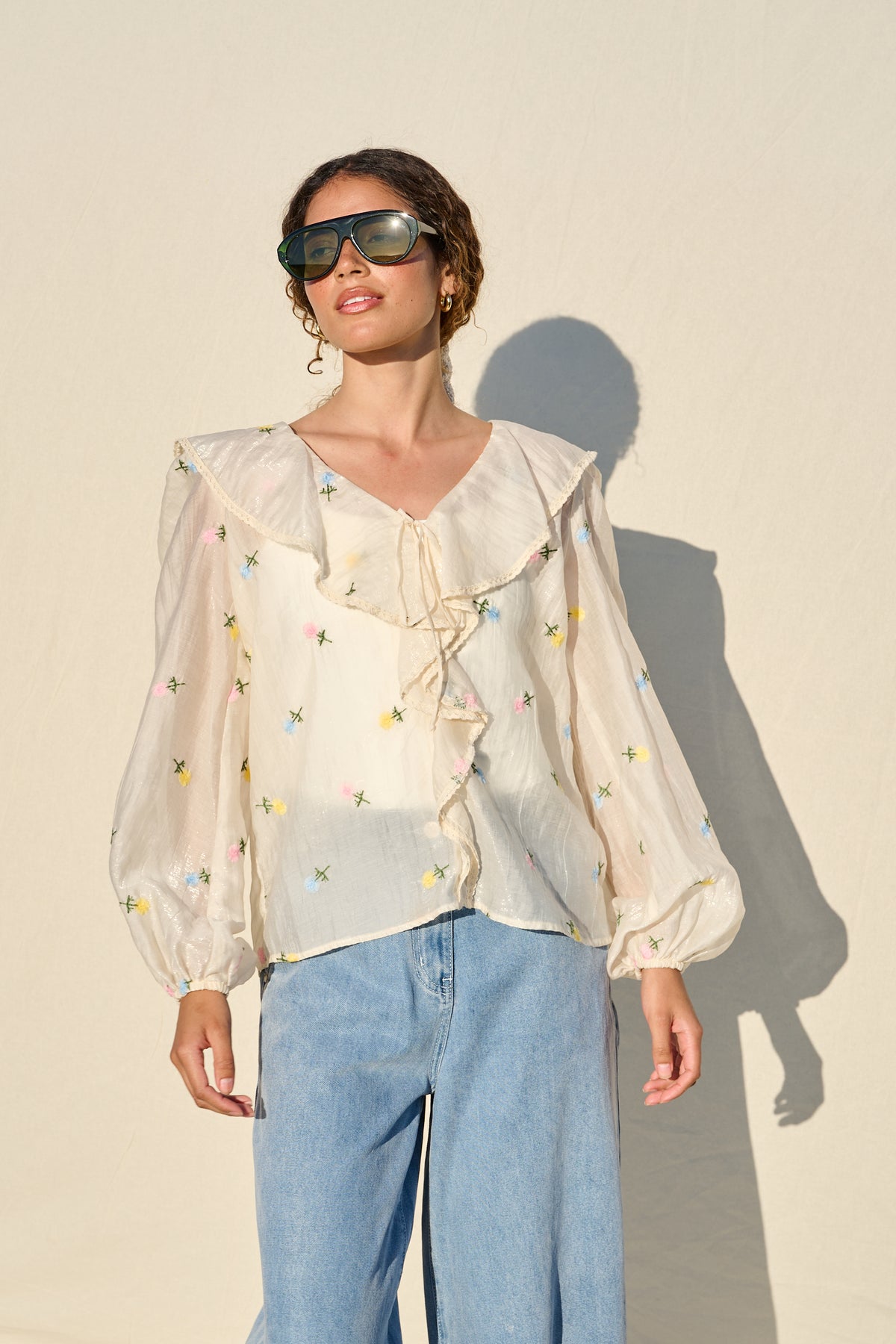 milk sheer blouse with floral embroidery, ruffle collar and tie front.