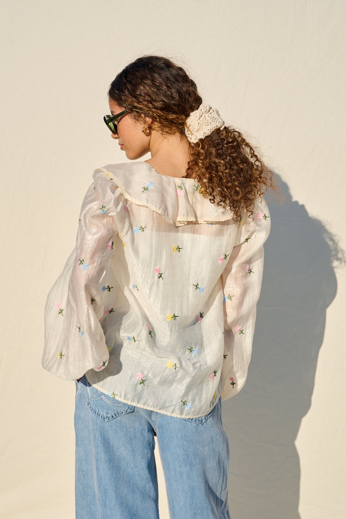 milk sheer blouse with floral embroidery, ruffle collar and tie front.