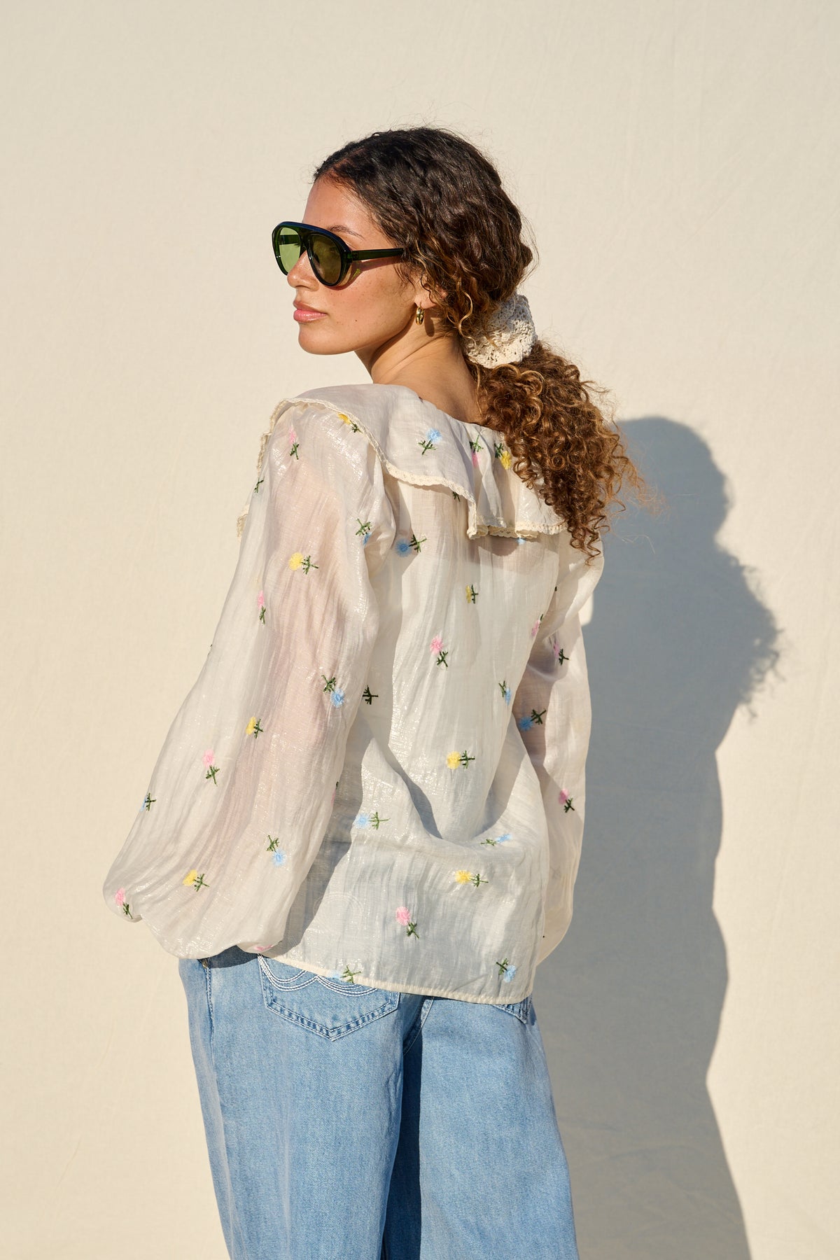 milk sheer blouse with floral embroidery, ruffle collar and tie front.