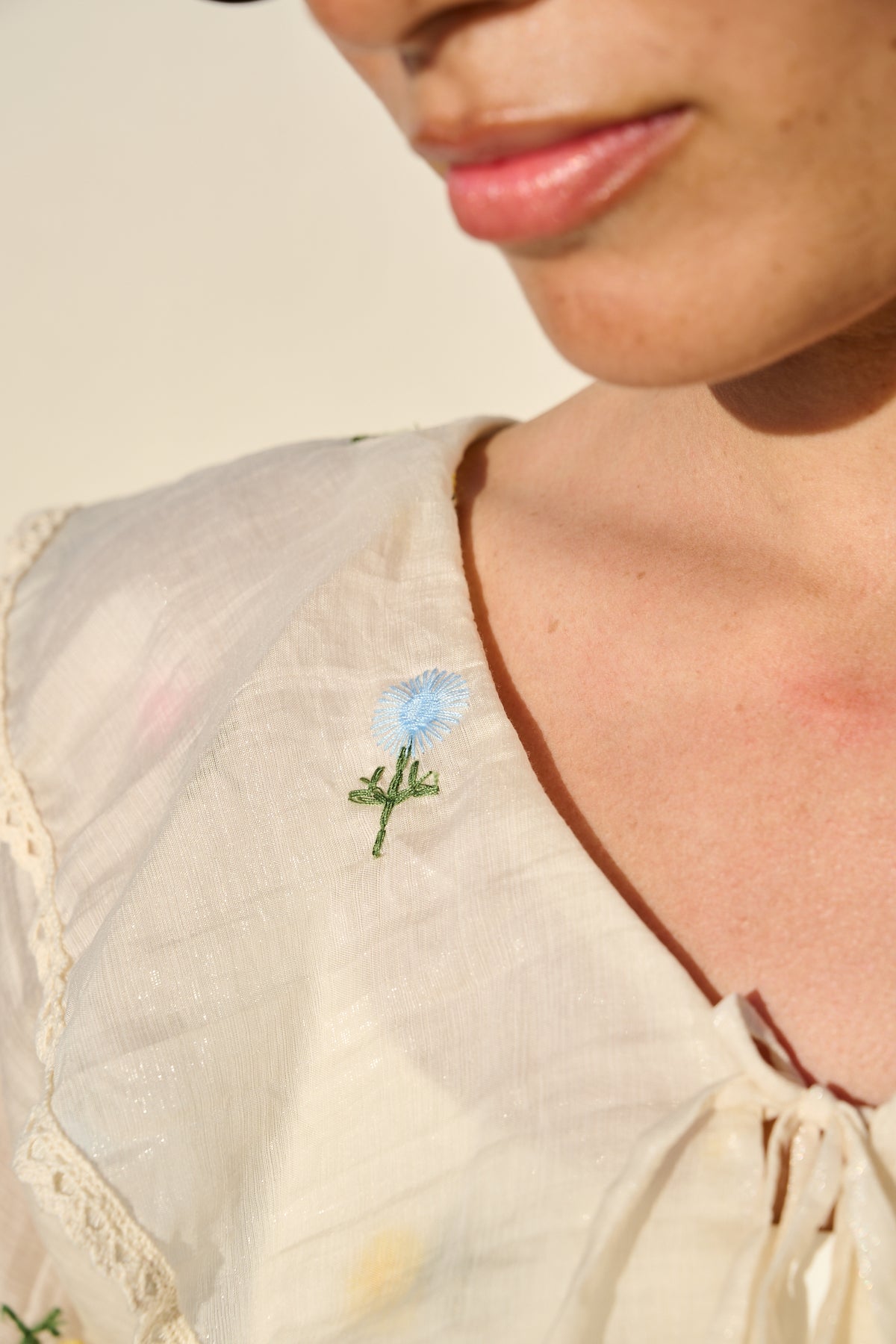 milk sheer blouse with floral embroidery, ruffle collar and tie front.