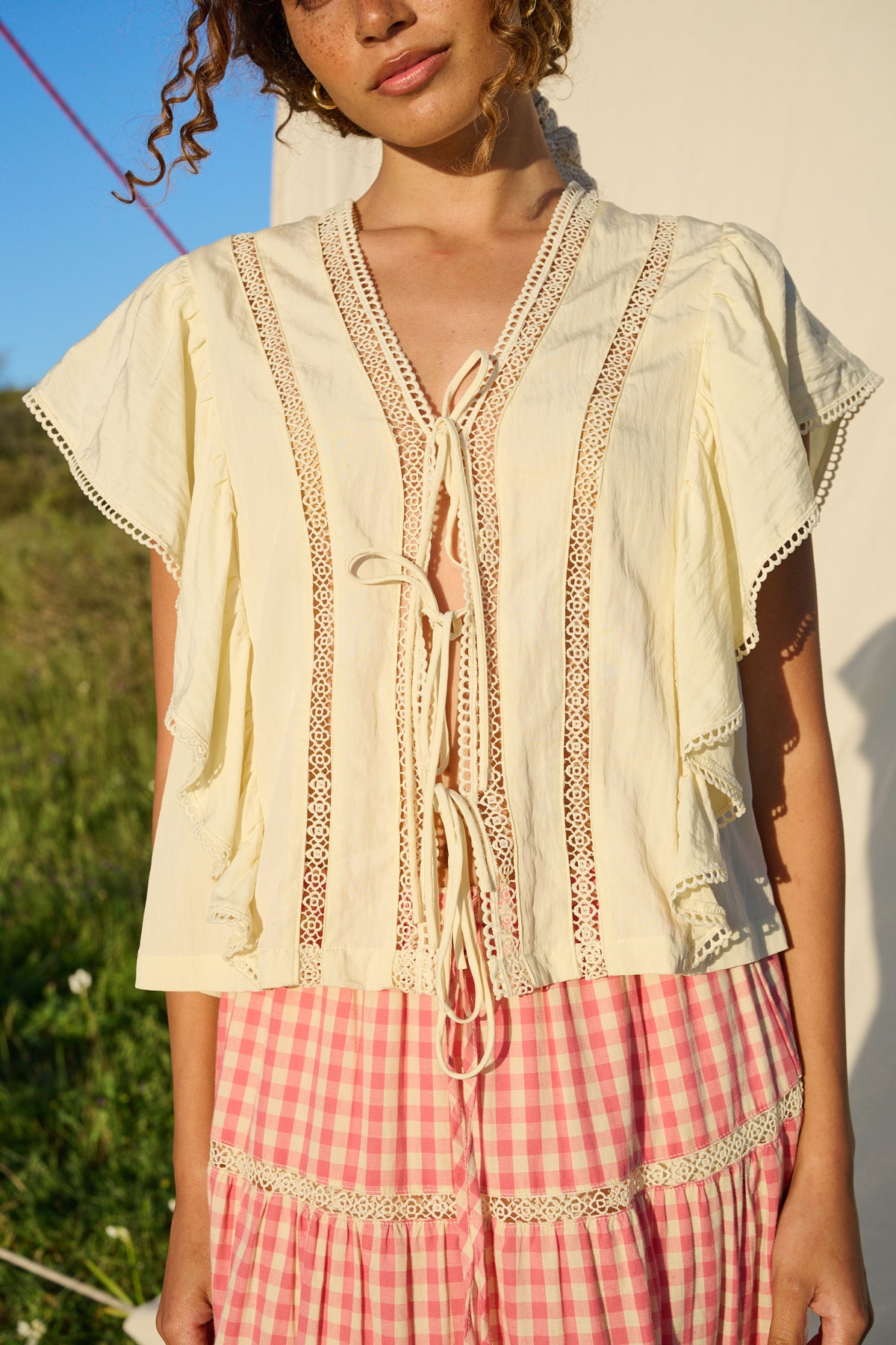 Butter yellow blouse with ruffle sleeves, lace trim and tie-front detail.