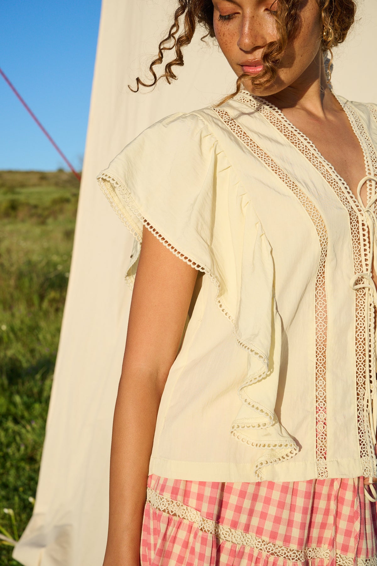Butter yellow blouse with ruffle sleeves, lace trim and tie-front detail.