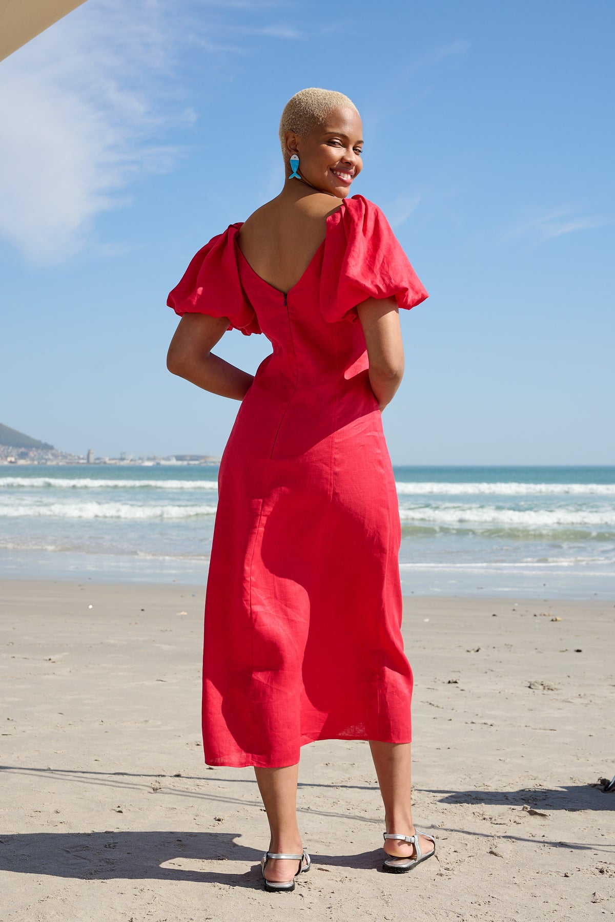 Woman wearing a red V-neck midi dress with puff sleeves on the beach