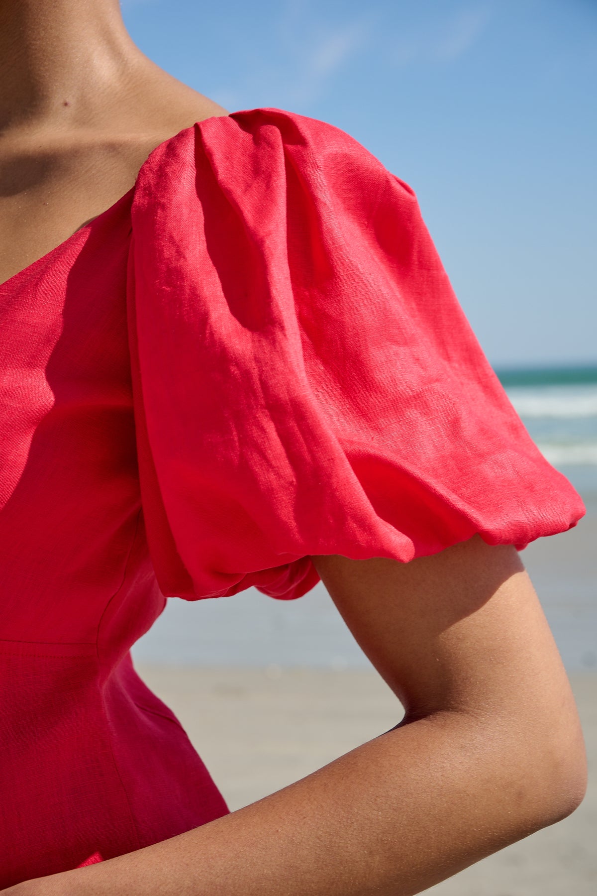 Woman wearing a red V-neck midi dress with puff sleeves on the beach