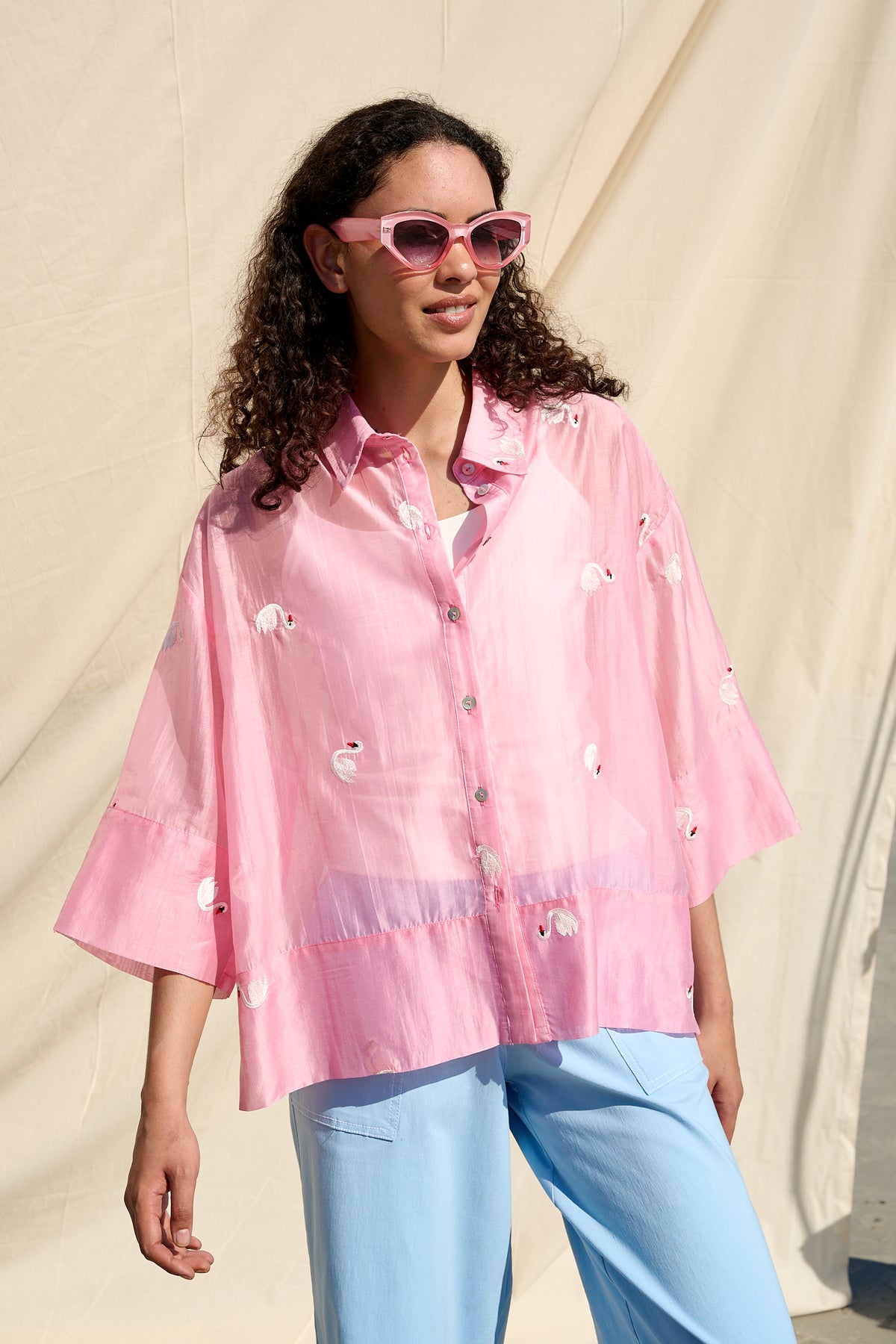 Pink oversized button-up shirt with embroidered swans and wide cuffs