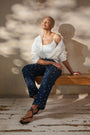 Model is wearing dark wash straight jeans with pearl details and a white shirt
