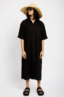 Model is wearing a black Linen Shirt Dress with short sleeves, a pocket and white contrast stitching 