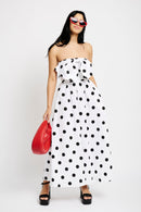 Model is wearing a black and white polka dot bustier top with a matching midi skirt. She's paired it with a red clutch bag and red sunglasses