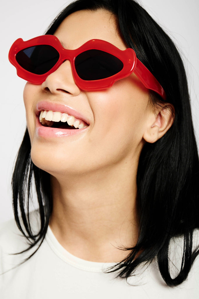 model wearing red sunglasses and white tee.