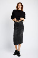 MODEL WEARING BLACK JUMPER AND BLACK DENIM SKIRT